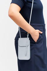 Profile view of model wearing the Oroton Margot Phone Crossbody in Dusk Blue and Pebble leather for Women .