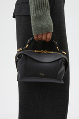 Profile view of model wearing the Oroton Mica Mini Bowler in Black and Premium pebble leather for Women .