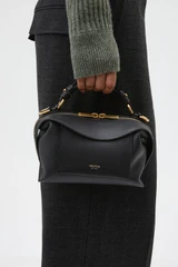 Profile view of model wearing the Oroton Mica Mini Bowler in Black and Premium pebble leather for Women .