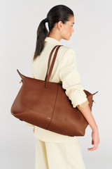Profile view of model wearing the Oroton Lilly Weekender Tote in Cognac and Pebble leather for Women .