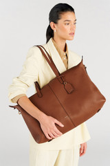 Profile view of model wearing the Oroton Lilly Weekender Tote in Cognac and Pebble leather for Women .