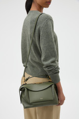 Profile view of model wearing the Oroton Mica Bowler in Dark Khaki and Premium pebble grain leather for Women .