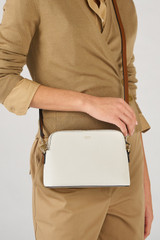 Profile view of model wearing the Oroton Iris Double Zip Crossbody in Cream and Premium pebble leather  for Women .
