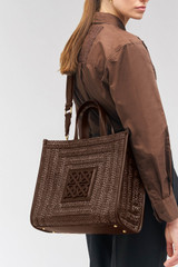 Profile view of model wearing the Oroton Lane Straw Medium Tote in Mahogany and Woven straw with leather trims for Women