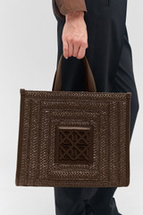 Profile view of model wearing the Oroton Lane Straw Medium Tote in Mahogany and Woven straw with leather trims for Women