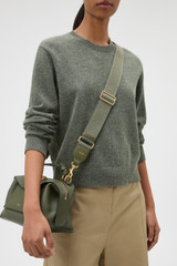 Profile view of model wearing the Oroton Logo Bag Strap in Dark Khaki and Smooth leather and webbing for Women .