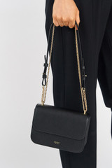 Profile view of model wearing the Oroton Lola Clutch in Black and Textured Leather for Women .