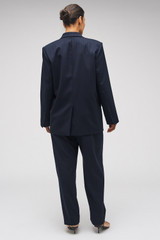 Profile view of model wearing the Oroton Tapered Pinstripe Pant in North Sea and 95% WOOL 5% ELASTANE for Women .