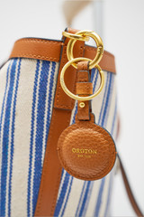 Profile view of model wearing the Oroton Fife Airtag Key Chain in Amber and Smooth leather material for Women .
