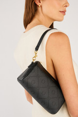 Profile view of model wearing the Oroton Harvey Signature Baguette Crossbody in Black and Nylon canvas base cloth material with PVC coating (70% PVC, 30% polyester) for Women .