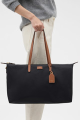 Profile view of model wearing the Oroton Lilly Nylon Weekender Tote in Black/Cognac and Nylon fabric for Women .