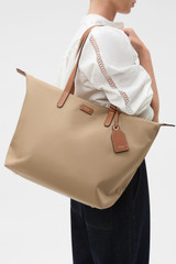 Profile view of model wearing the Oroton Lilly Nylon Light Weight Tote Bag in Mushroom/Cognac and Nylon fabric for Women .