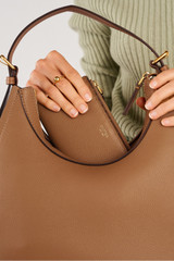 Profile view of model wearing the Oroton Eve Slim Zip Wallet in Tan and Premium pebble leather for Women .