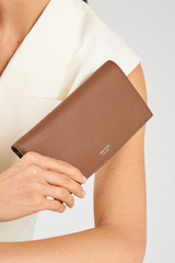 Profile view of model wearing the Oroton Eve Soft Fold Wallet in Tan and Premium pebble leather for Women .