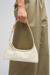Profile view of model wearing the Oroton Cinder Mini Baguette in Antique Cream and Crackle leather exterior for Women .