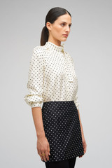 Profile view of model wearing the Oroton Spot Mini Skirt in Black/Cream and 100% Silk for Women