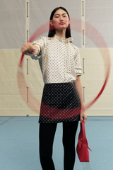 Profile view of model wearing the Oroton Spot Mini Skirt in Black/Cream and 100% Silk for Women .