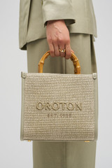 Profile view of model wearing the Oroton Lane Straw Tote in Laurel and Woven Straw With Leather Trim for Women