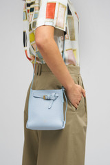 Profile view of model wearing the Oroton Margot Tiny Bucket Bag in Denim and Smooth Leather exterior for Women