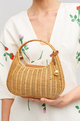 Profile view of model wearing the Oroton Clara Wicker Mini Bag in Natural/Cognac and Woven wicker exterior for Women .
