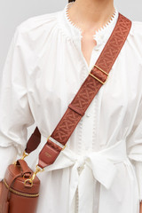 Profile view of model wearing the Oroton Logo Bag Strap in Barn Red and Premium leather and webbing material for Women .
