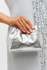Profile view of model wearing the Oroton Gretel Metallic Mini Top Handle in Silver and Foil texture leather for Women .