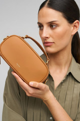 Profile view of model wearing the Oroton Margot Camera Bag in Dark Camel and Pebble Leather exterior for Women