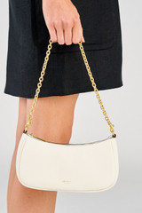 Profile view of model wearing the Oroton Eve Mini Baguette in Cream and Pebble leather material for Women .