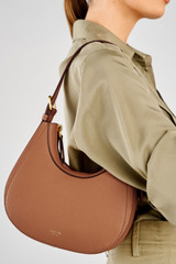 Profile view of model wearing the Oroton Dylan Mini Hobo in Tan and Premium pebble leather for Women .