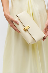 Profile view of model wearing the Oroton Etta Medium Clutch in Antique Cream and Premium smooth leather for Women .