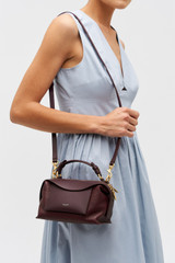 Profile view of model wearing the Oroton Mica Mini Bowler in Currant and Premium pebble leather for Women .