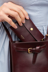 Profile view of model wearing the Oroton Margot Keyring Pouch in Currant and Premium smooth leather for Women .