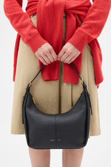 Profile view of model wearing the Oroton Dorit Small Hobo Bag in Black and Premium pebble leather for Women .