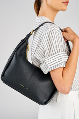 Profile view of model wearing the Oroton Dorit Small Hobo Bag in Black and Premium pebble leather for Women .
