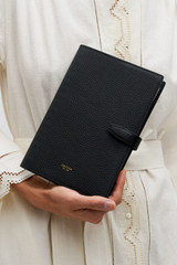 Profile view of model wearing the Oroton Fife A5 Notebook in Black and Pebble leather material for Women .