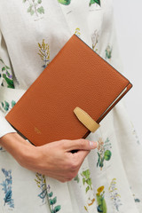 Profile view of model wearing the Oroton Fife A5 Notebook in Amber and Pebble leather material for Women .