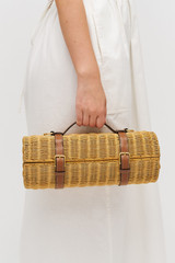 Profile view of model wearing the Oroton Billie Wicker Wine Holder in Brandy and Wicker exterior with leather trims for Women .