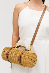 Profile view of model wearing the Oroton Billie Wicker Wine Holder in Brandy and Wicker exterior with leather trims for Women .