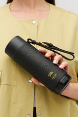 Profile view of model wearing the Oroton Frank Green X Oroton  595Ml Bottle in Black and Stainless steel water bottle with Oroton pebble leather sleeve and wristlet for Women .