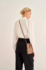 Profile view of model wearing the Oroton Dylan Phone Crossbody in Tan and Premium pebble leather for Women .