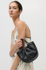 Profile view of model wearing the Oroton Emilia Soft Mini Tote in Black and Smooth leather exterior for Women . IP:3