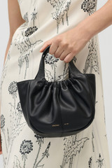 Profile view of model wearing the Oroton Emilia Soft Mini Tote in Black and Smooth leather exterior for Women . IP:5