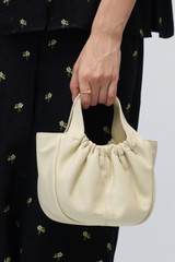 Profile view of model wearing the Oroton Emilia Soft Mini Tote in French Vanilla and Smooth leather exterior for Women .