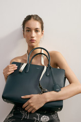 Profile view of model wearing the Oroton Muse 15" Worker Tote in Aniseed and Saffiano leather exterior for Women .