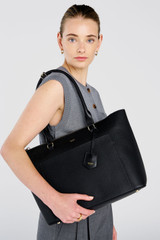 Profile view of model wearing the Oroton IRIS MEDIUM TOTE in Black and Premium pebble leather for Women .