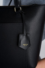 Profile view of model wearing the Oroton Iris Small Tote in Black and Premium pebble leather for Women .