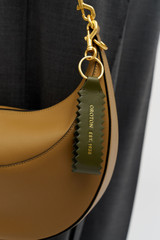 Profile view of model wearing the Oroton Zig Zag Keyring in DARK KHAKI and Premium crackle leather for Women .