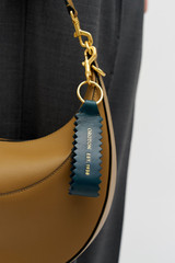 Profile view of model wearing the Oroton Zig Zag Keyring in ANISEED and Premium crackle leather for Women .