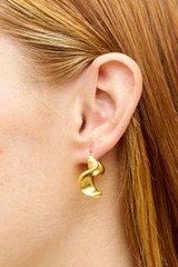 Profile view of model wearing the Oroton Wave Hoops in Worn Gold and Premium brass material for Women .