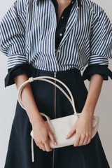 Profile view of model wearing the Oroton Breeze Baguette in Clotted Cream and Premium smooth leather for Women .
